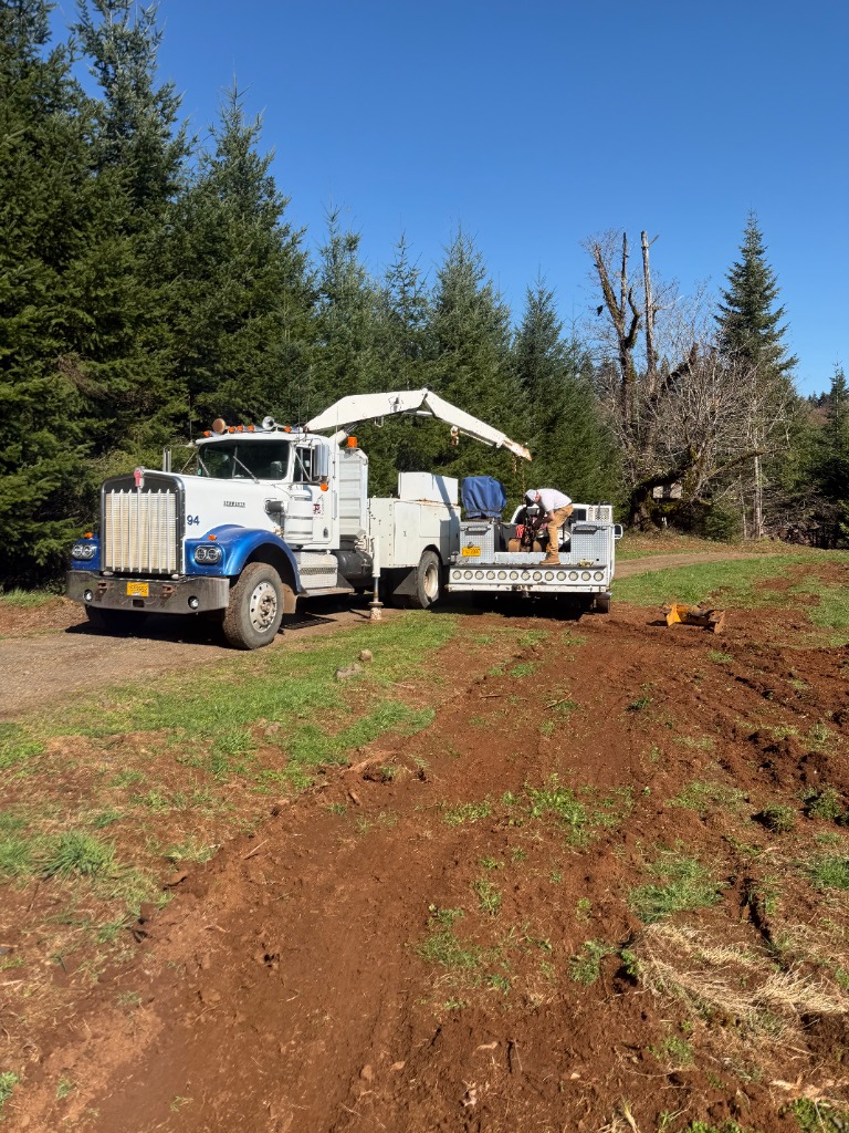 Kenworth crane truck #94 deployed on dirt grade with outriggers servicing machinery in Oregon